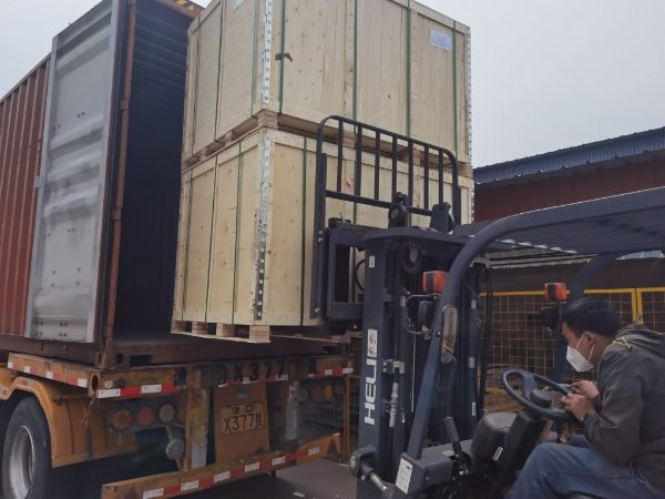 The forklift is used to load the wooden case into the truck compartment.