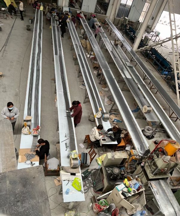 Workers are installing ferrules on stainless steel rope mesh.