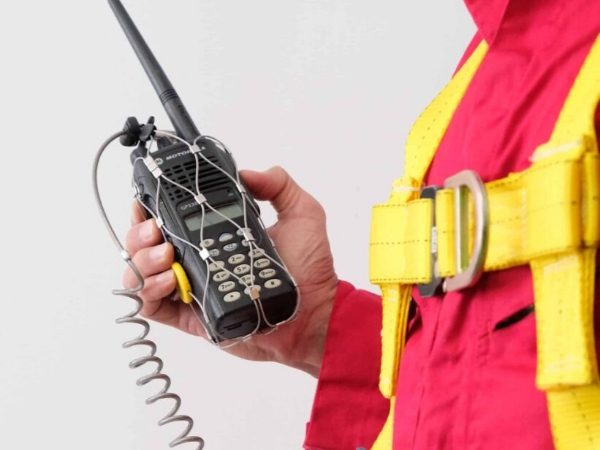 A man is holding a walkie-talkie fixed by a rope mesh.