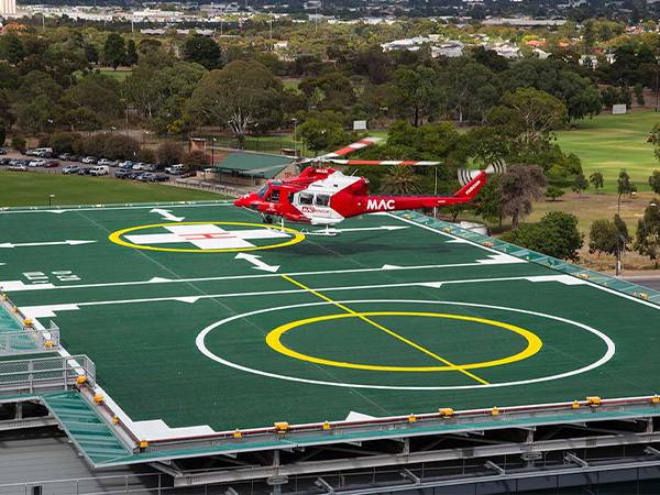 A helicopter is landing on the elevated helipad with helideck safety net