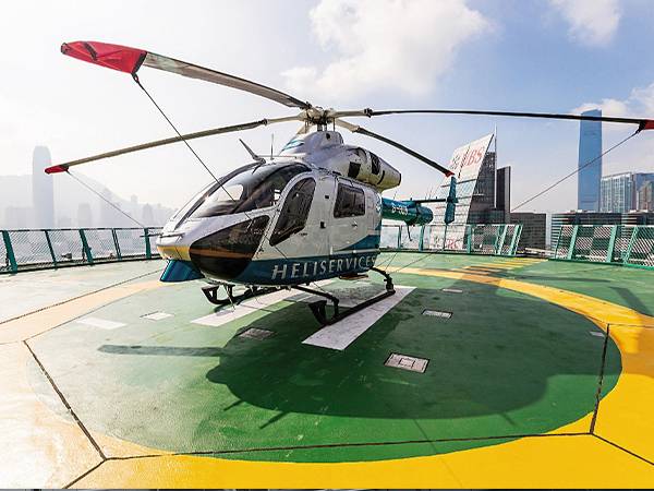 A helicopter is landed on a hotel helipad enclosed with helideck safety net.