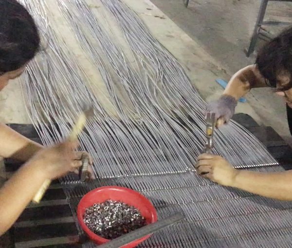 3 workers are installing ferrules on stainless steel rope mesh.