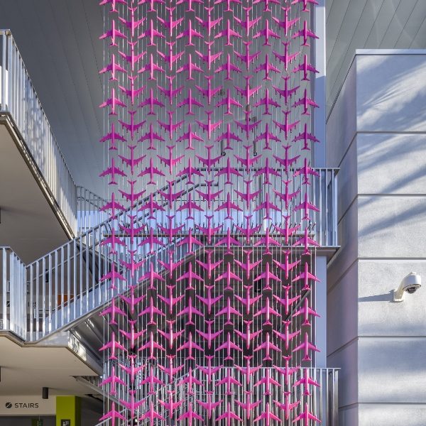 Many s pink airplanes are secured by stainless steel rope systems on the wall.